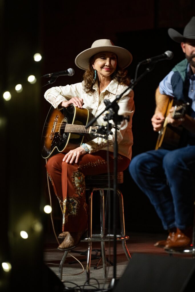 Pam Tillis playing guitar and singing at Storytellers Unplugged event in Abilene, TX.